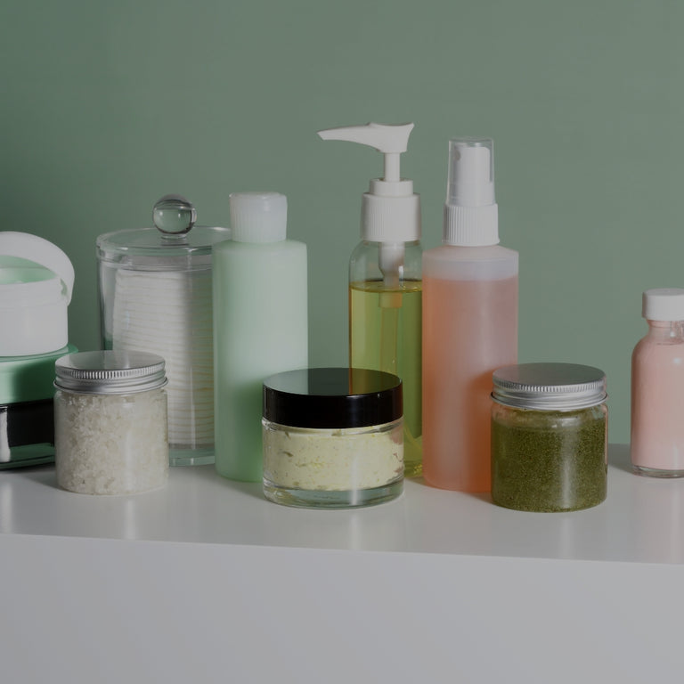 Collection of skincare products on a white surface with a green background