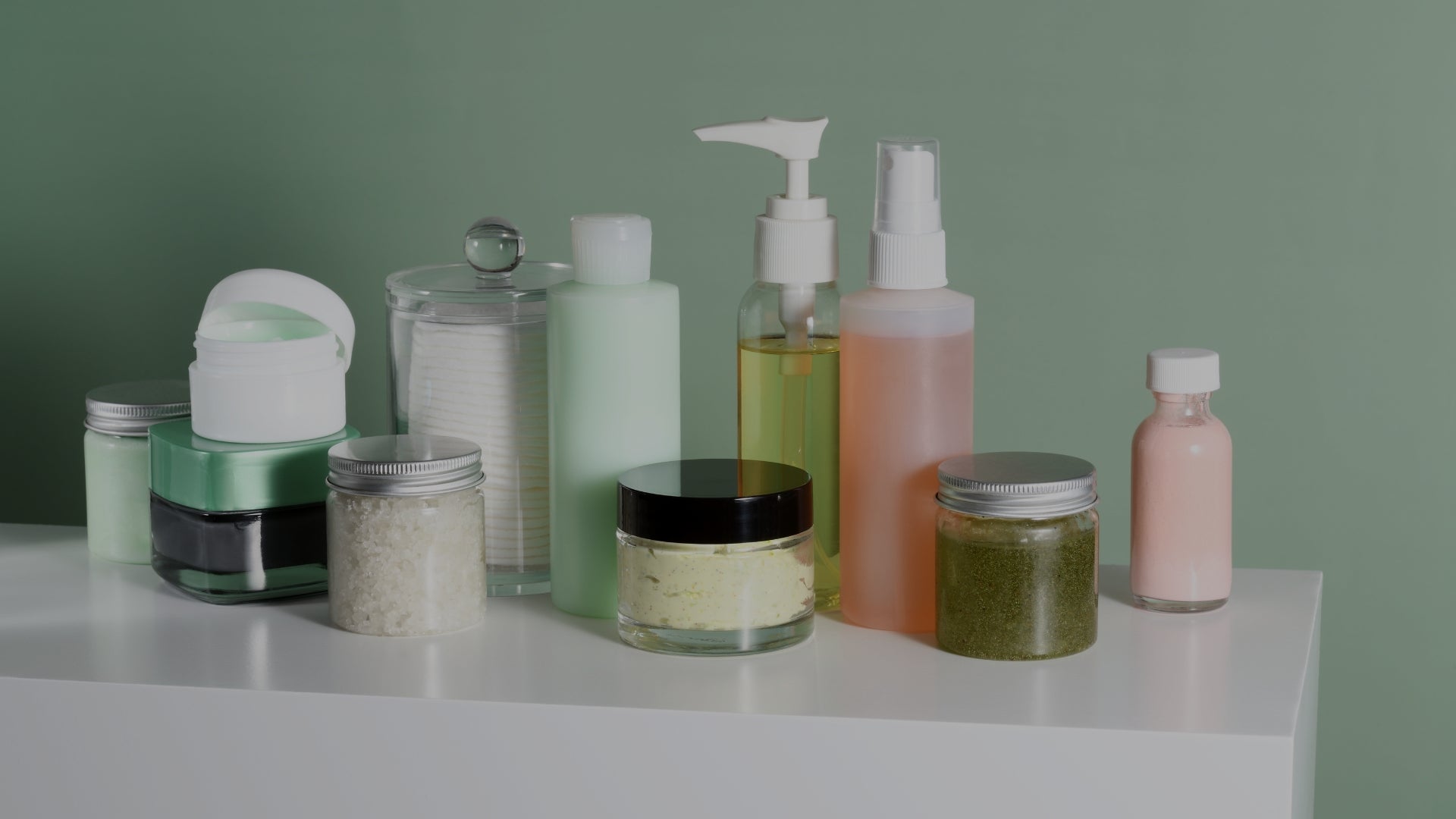 Collection of skincare products on a white surface with a green background